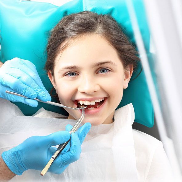 A little girl is getting her teeth examined by a dentist