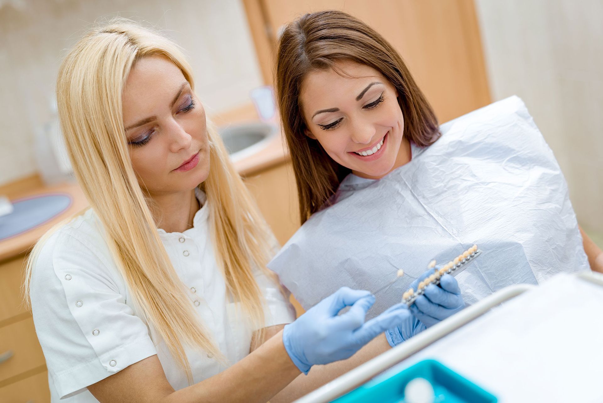 Dentist showing shade samples to patient in dental office.