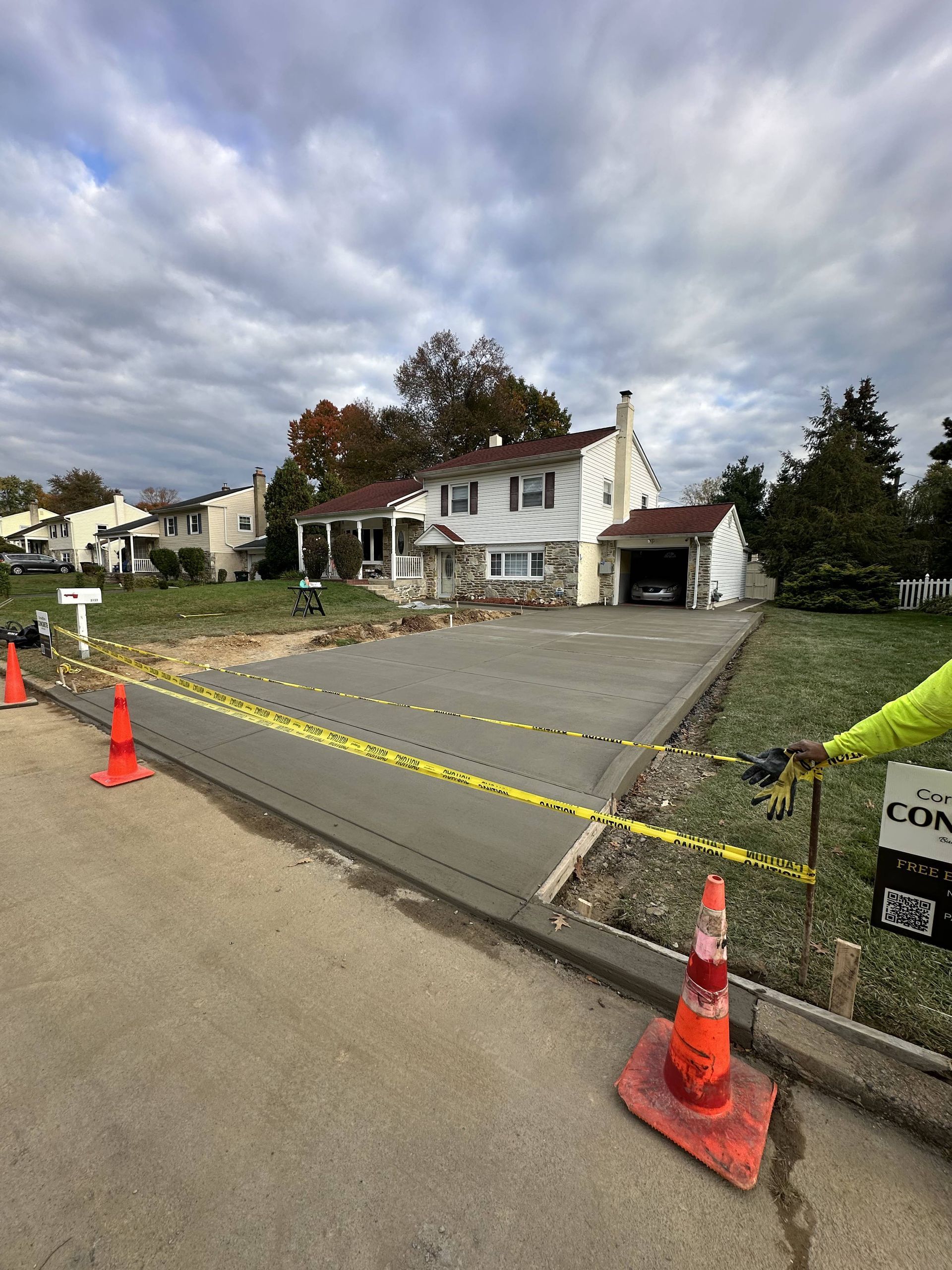 Freshly poured concrete driveway in front of a house, roped off with caution tape.