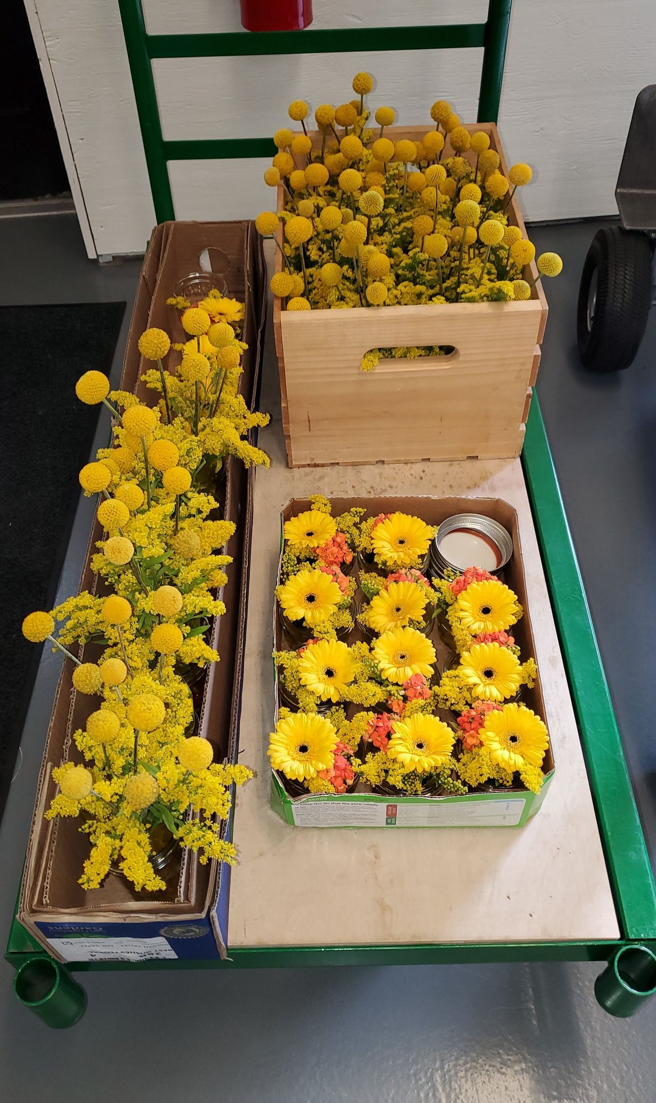 Three boxes of yellow flowers are sitting on a table.