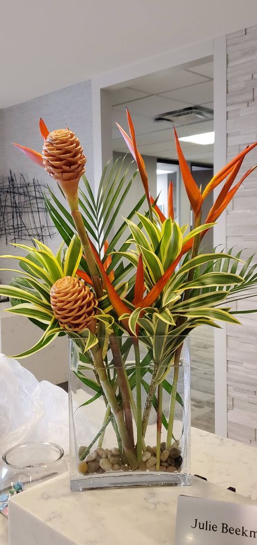 A vase filled with flowers and plants is sitting on a table.