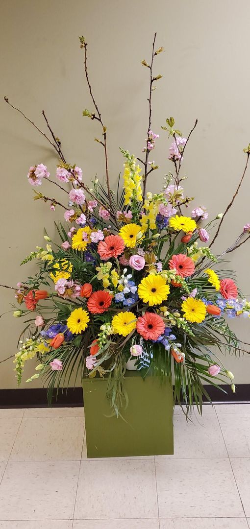 A large vase filled with colorful flowers is sitting on the floor.