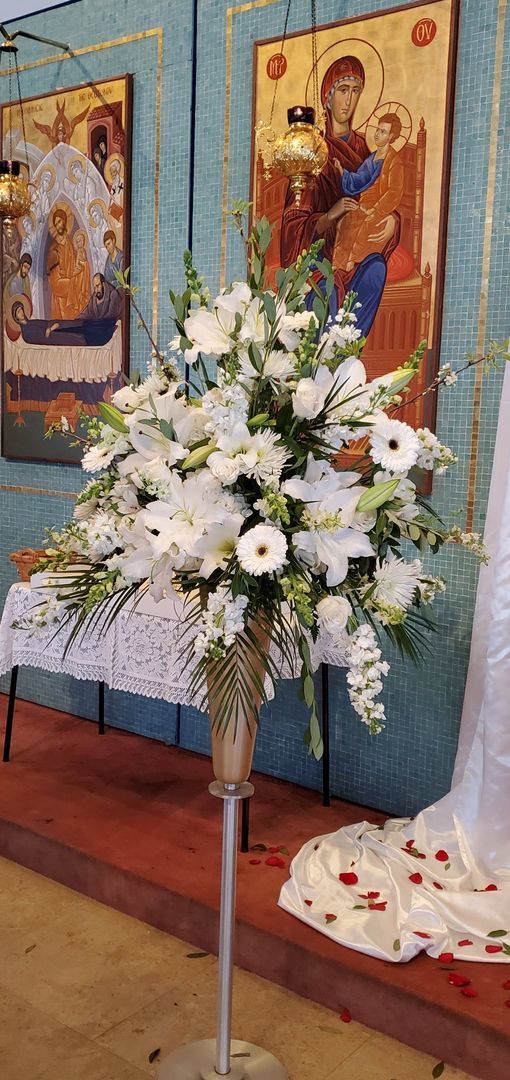 A vase filled with white flowers is sitting on a table in a church.