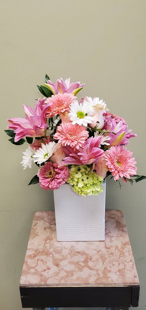 A vase filled with pink and white flowers is sitting on a table.