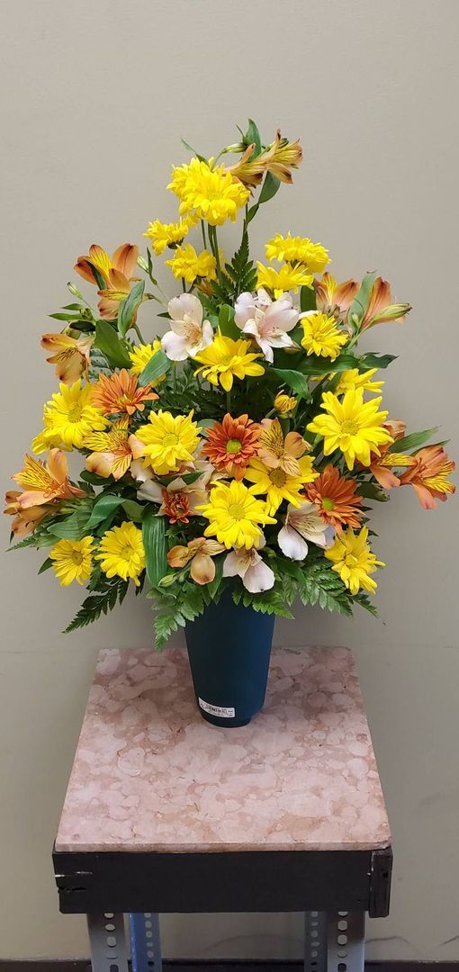 A vase filled with yellow and orange flowers is sitting on a table.