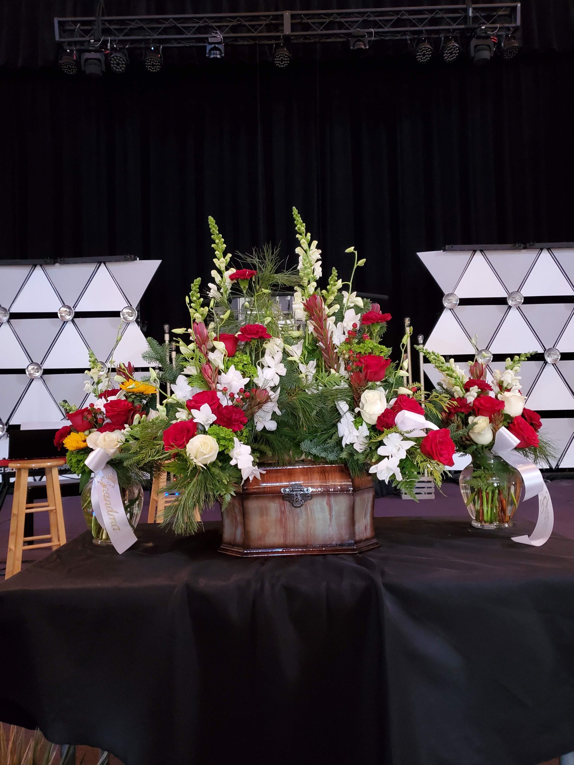 A table with a vase of flowers on it in front of a stage.