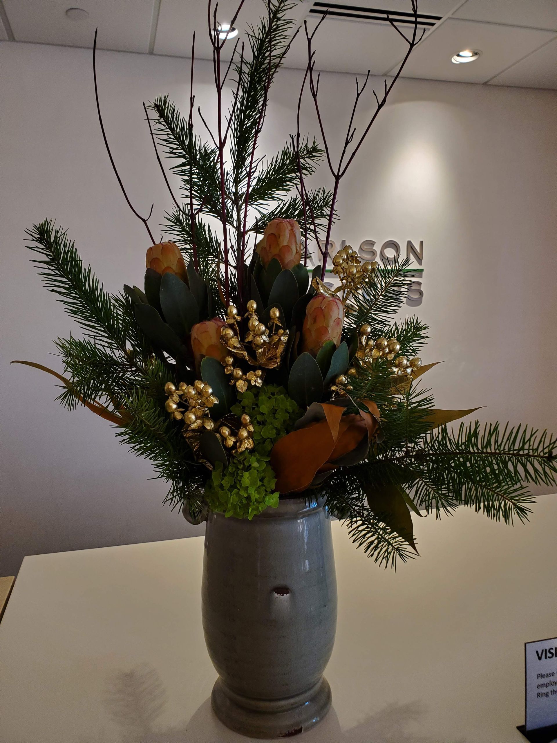 A vase filled with flowers in front of a sign.