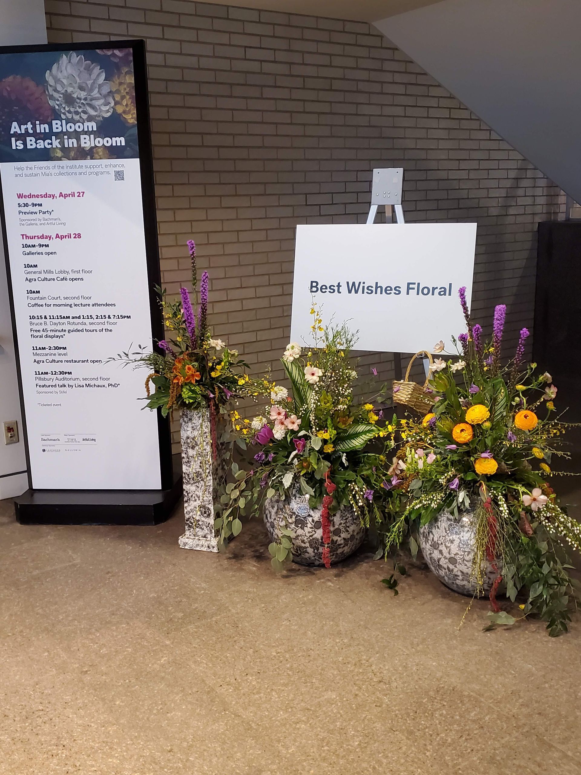 A sign in a room with flowers in front of it.