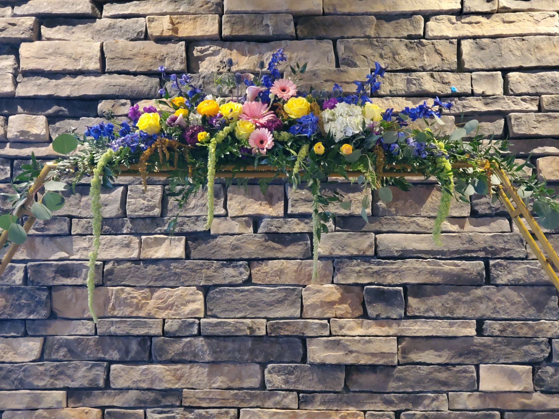 A brick wall with a floral arch in front of it.