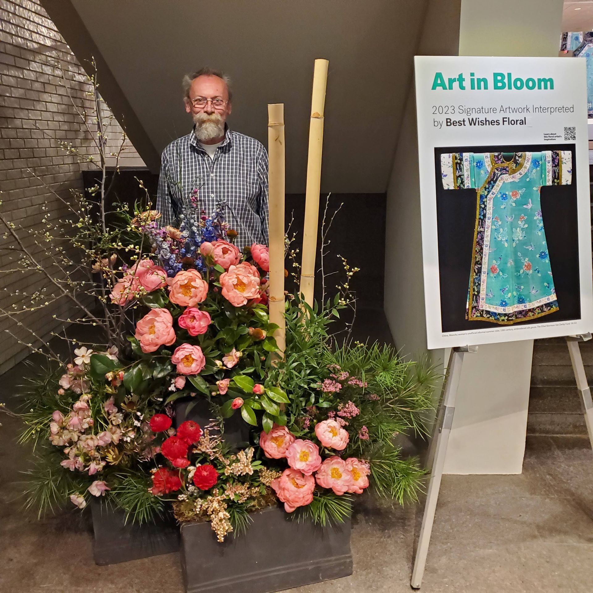 A man stands in front of a sign that says art in bloom.