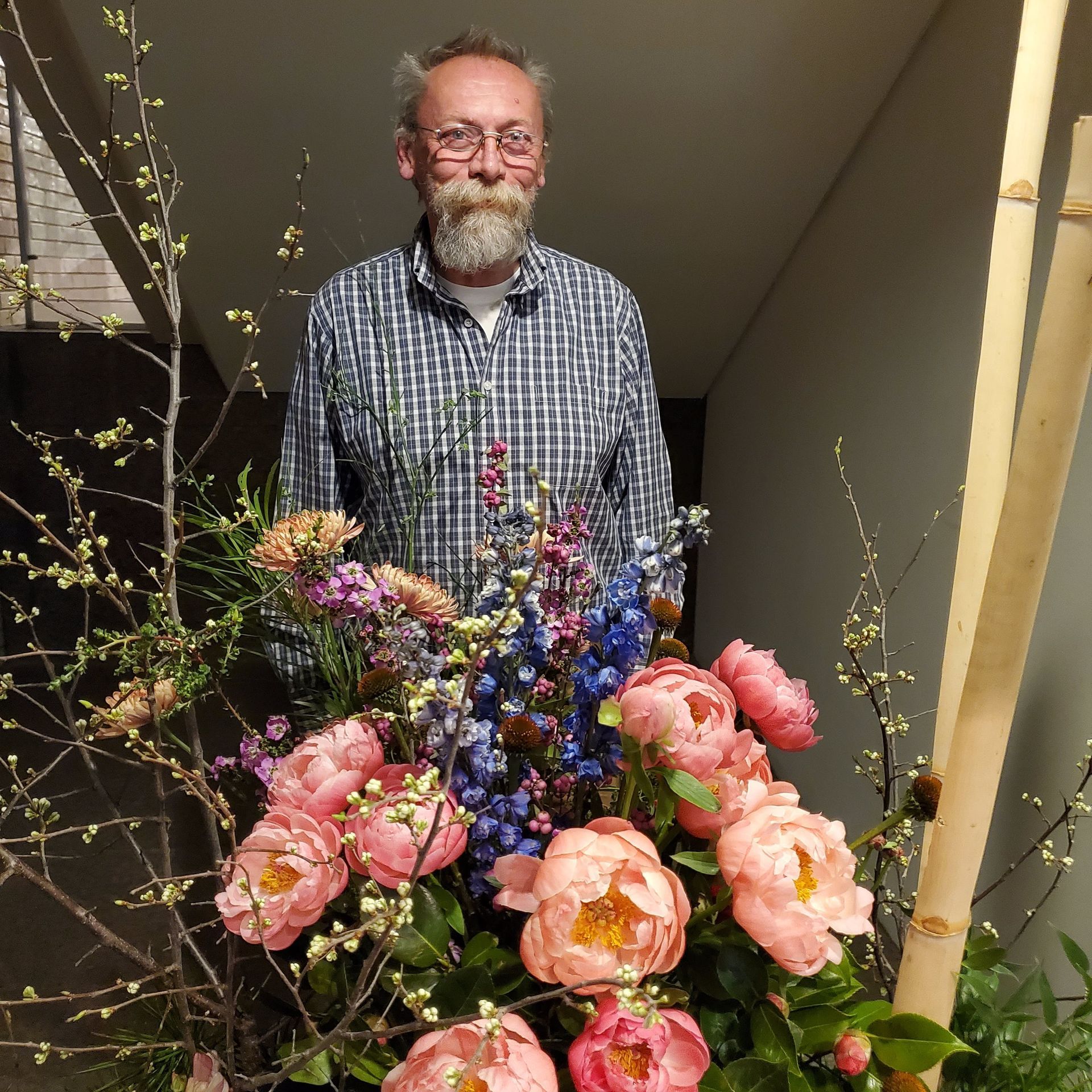 A man standing in front of a bunch of flowers.