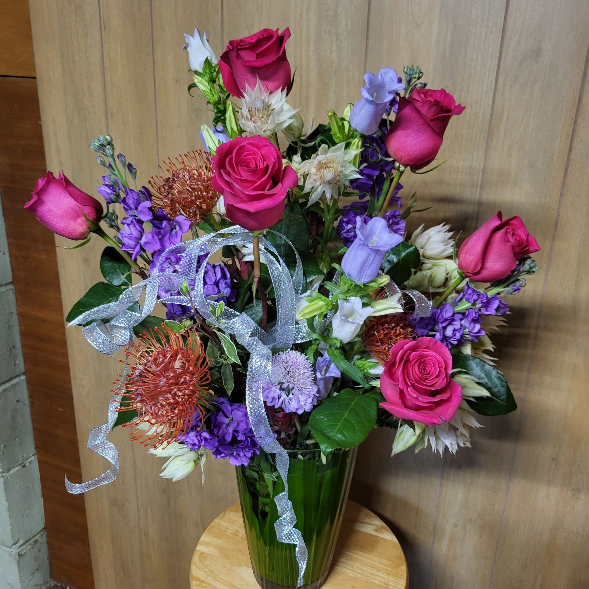 A vase filled with pink roses and purple flowers.