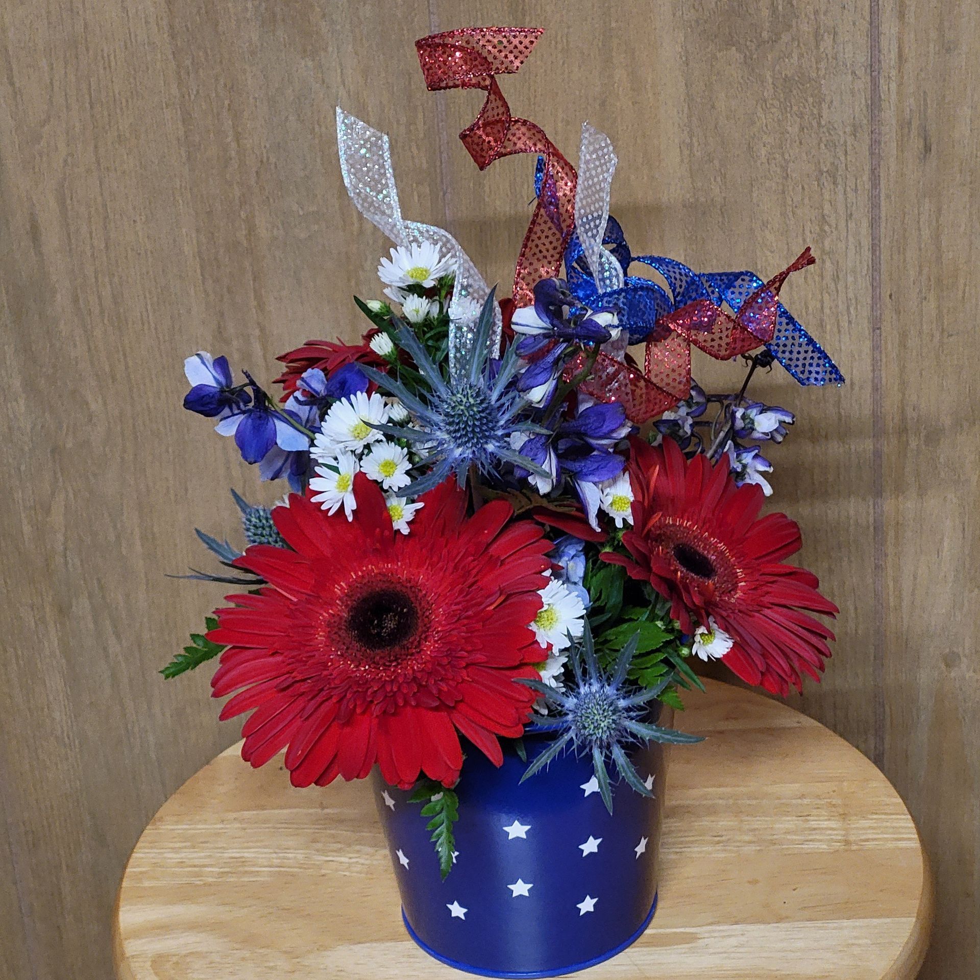 A blue vase filled with red white and blue flowers.