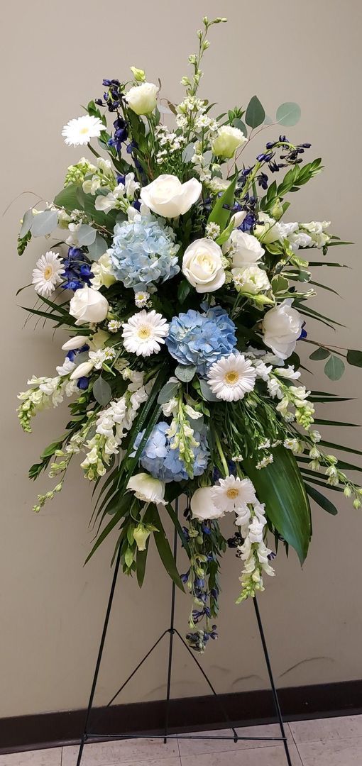 A display of blue and white flowers on a stand in a room.