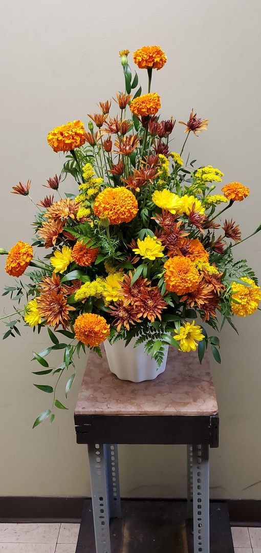 A vase filled with yellow and orange flowers is sitting on a table.