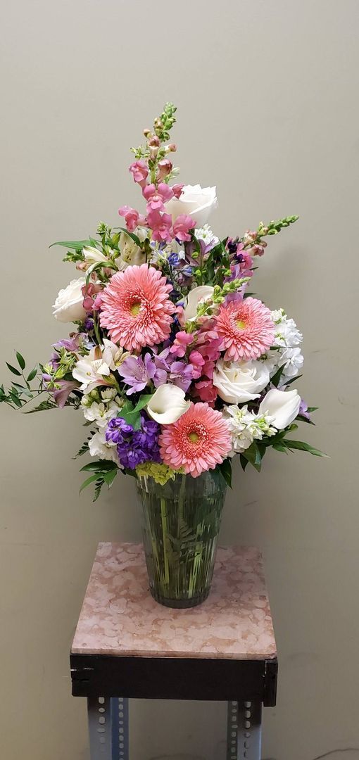 A vase filled with pink and purple flowers is sitting on a table.