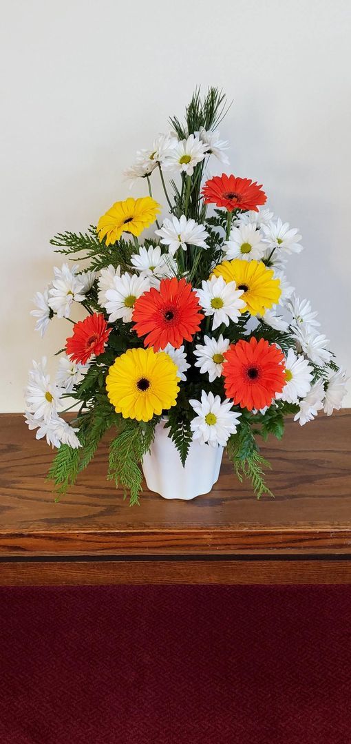 A vase filled with flowers is sitting on a wooden table.