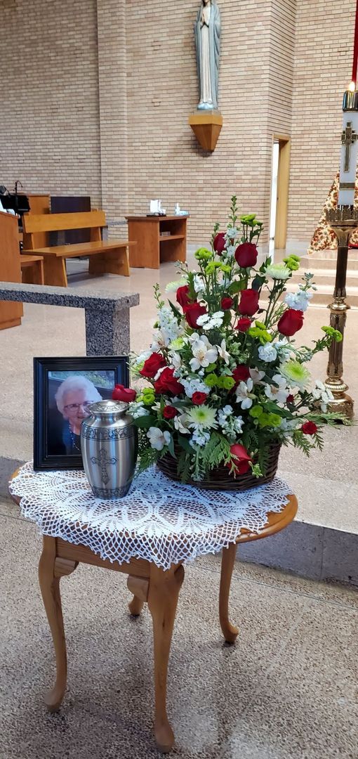 A table with flowers and an urn on it in a church.