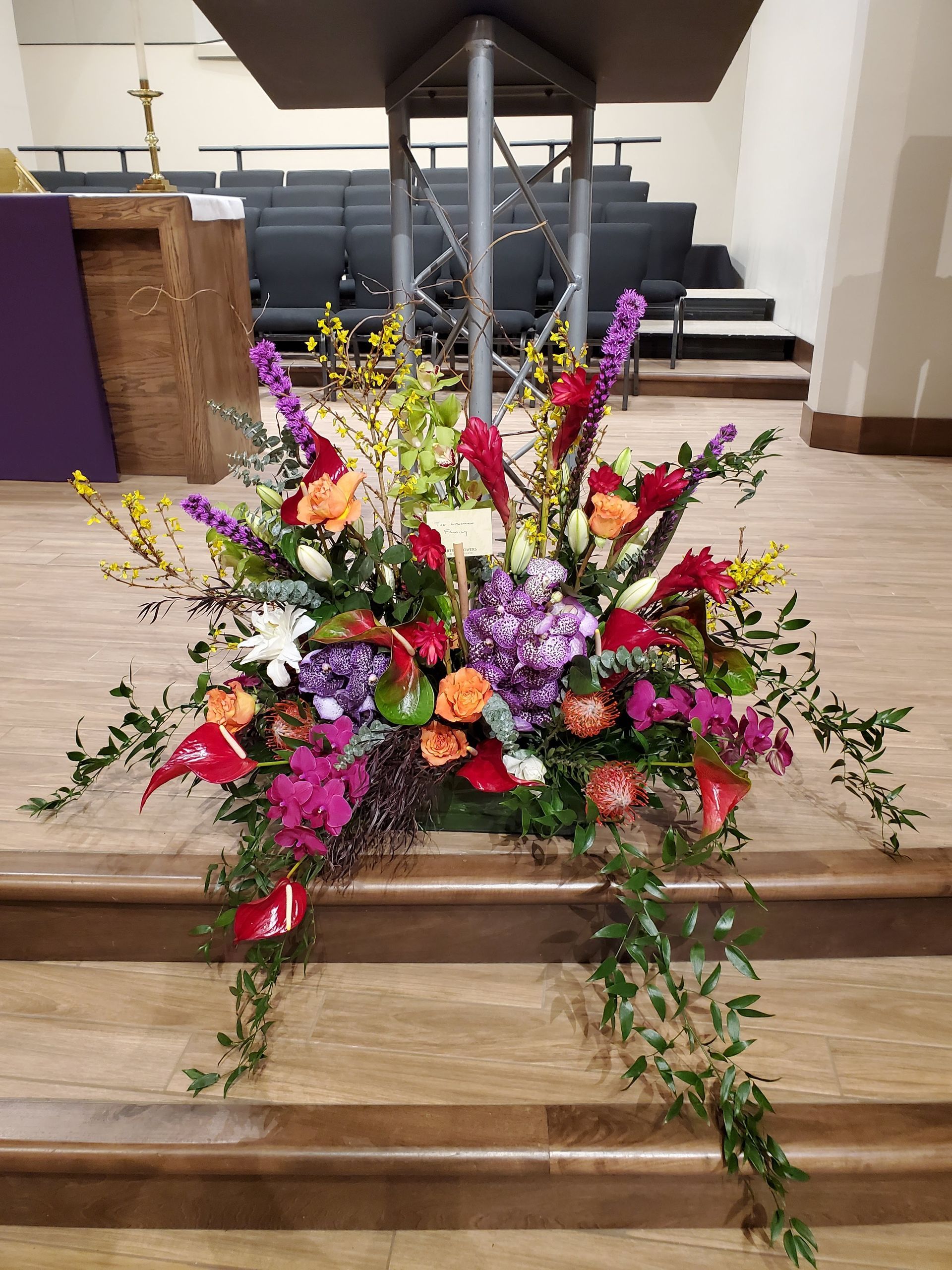 A large bouquet of flowers is sitting on top of a wooden podium in a church.