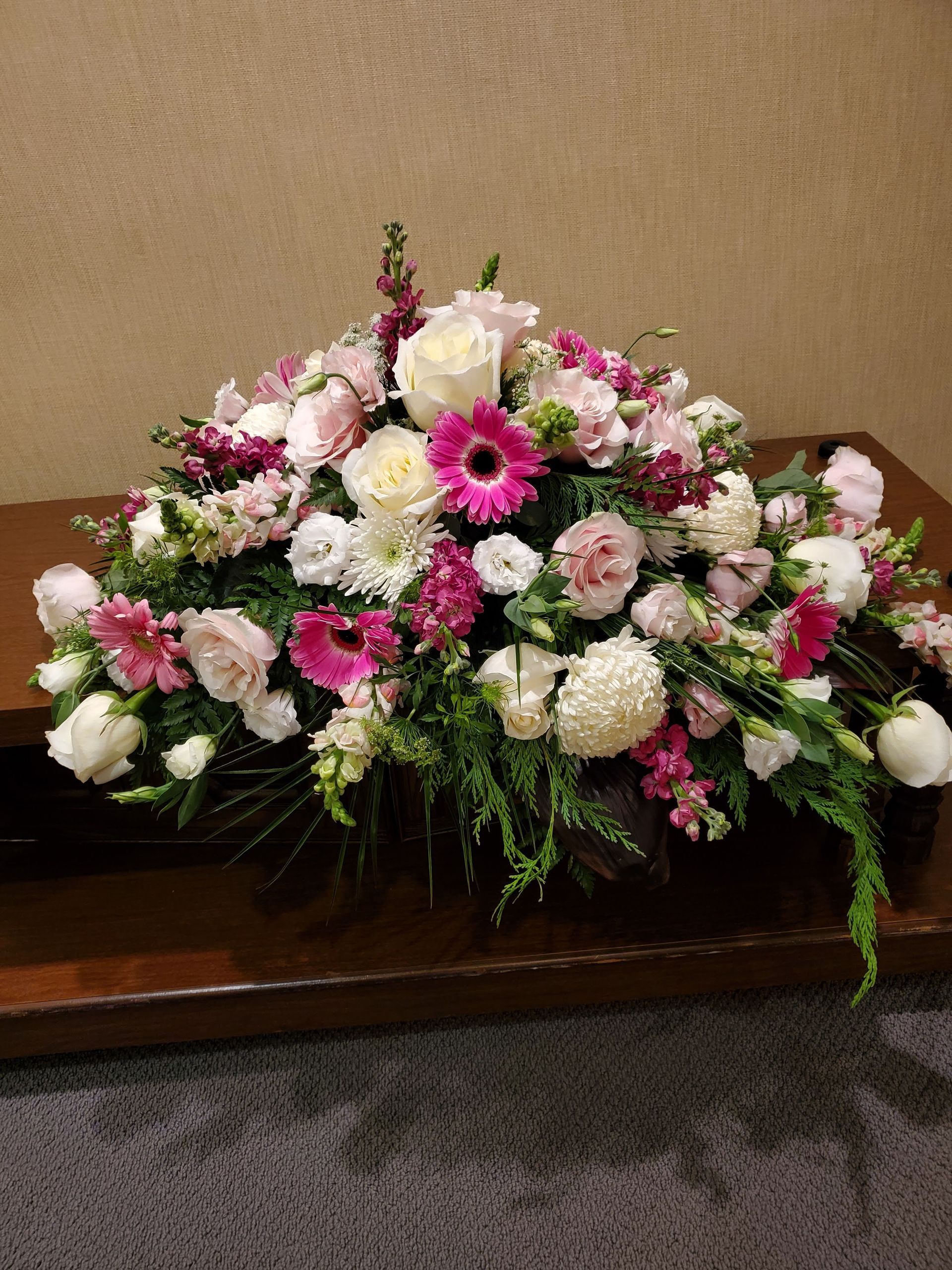A large bouquet of pink and white flowers is sitting on a wooden table.