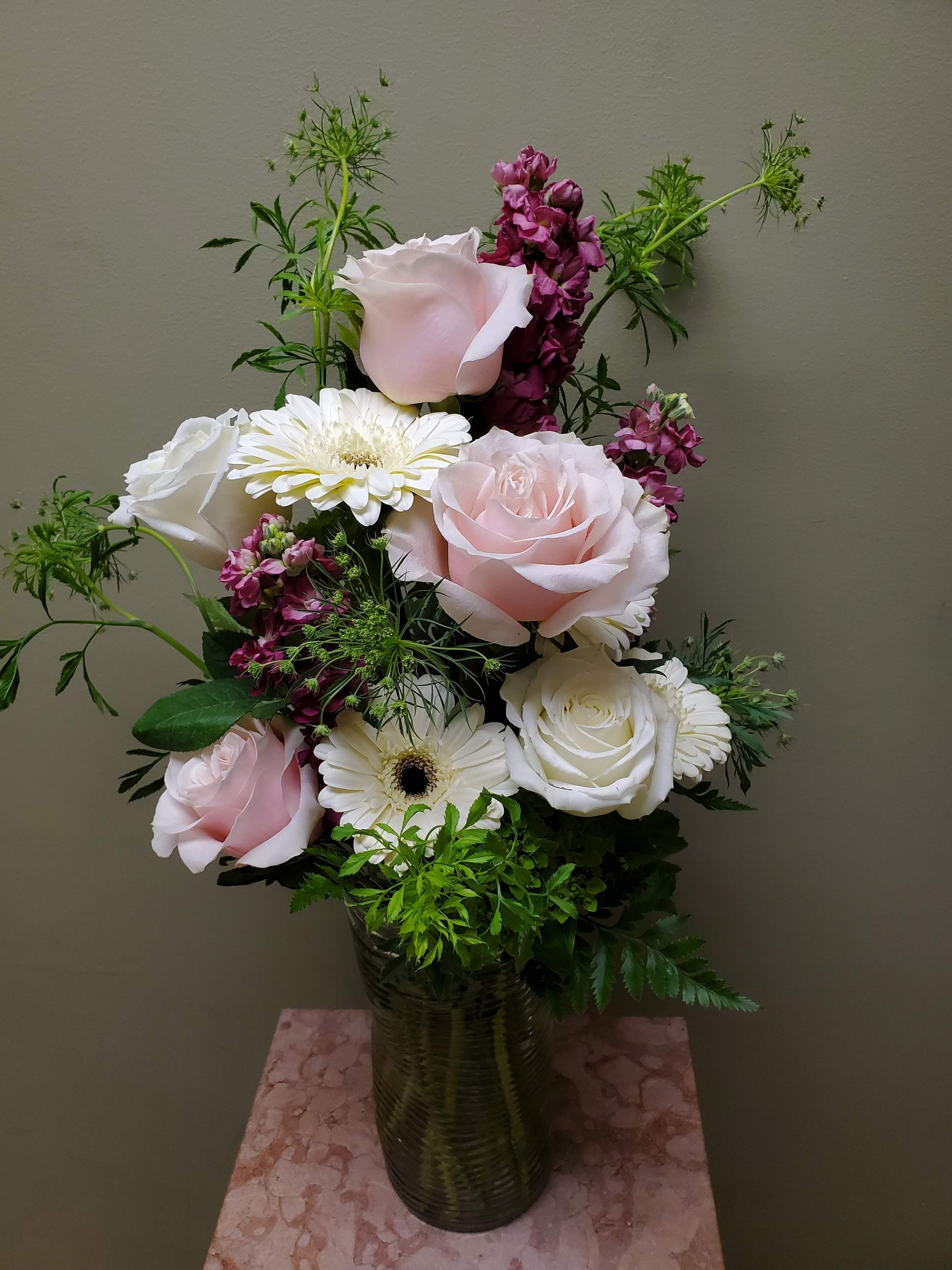 A vase filled with pink and white flowers is sitting on a table.