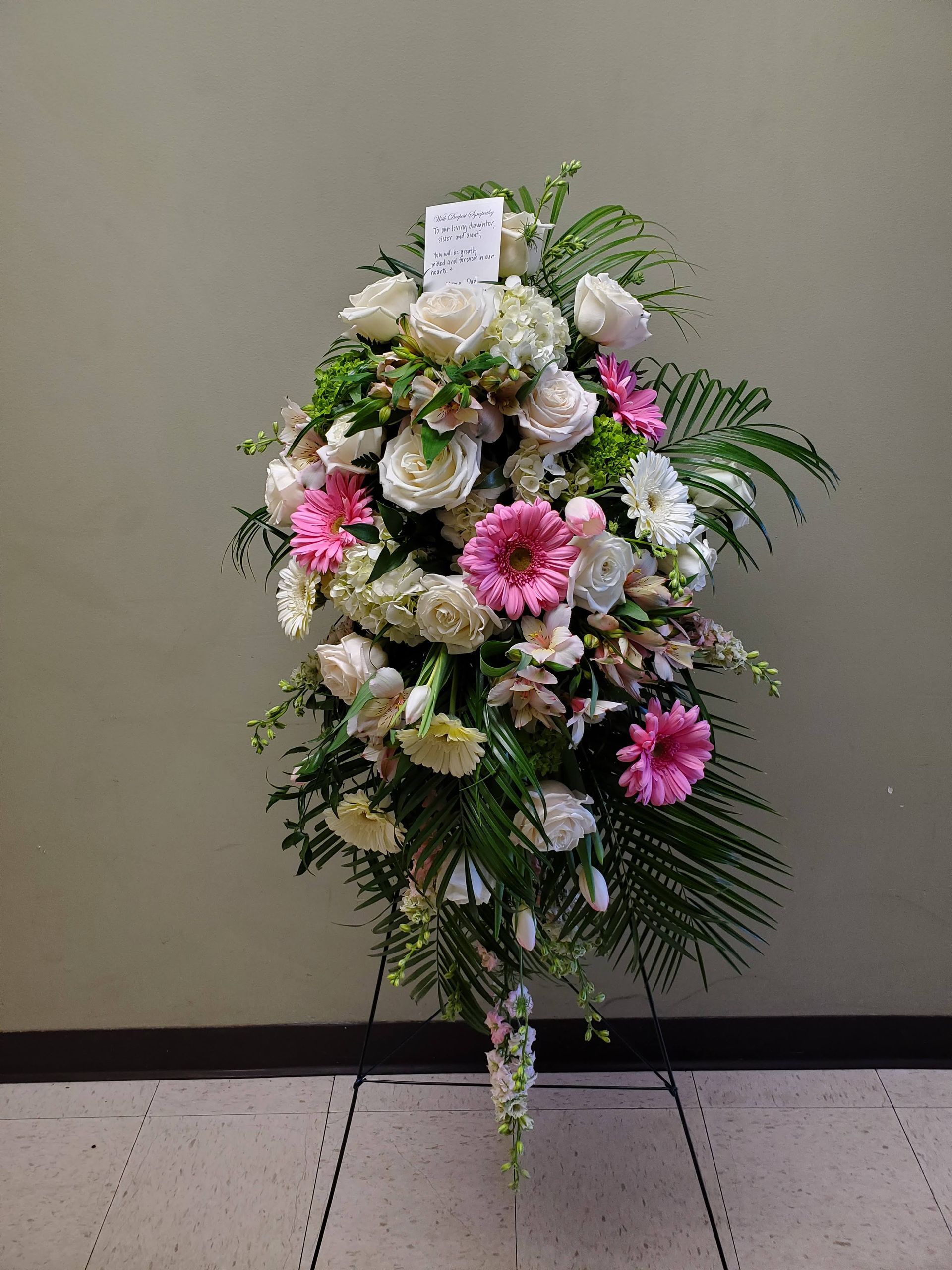 A wreath of pink and white flowers is sitting on a tiled floor.