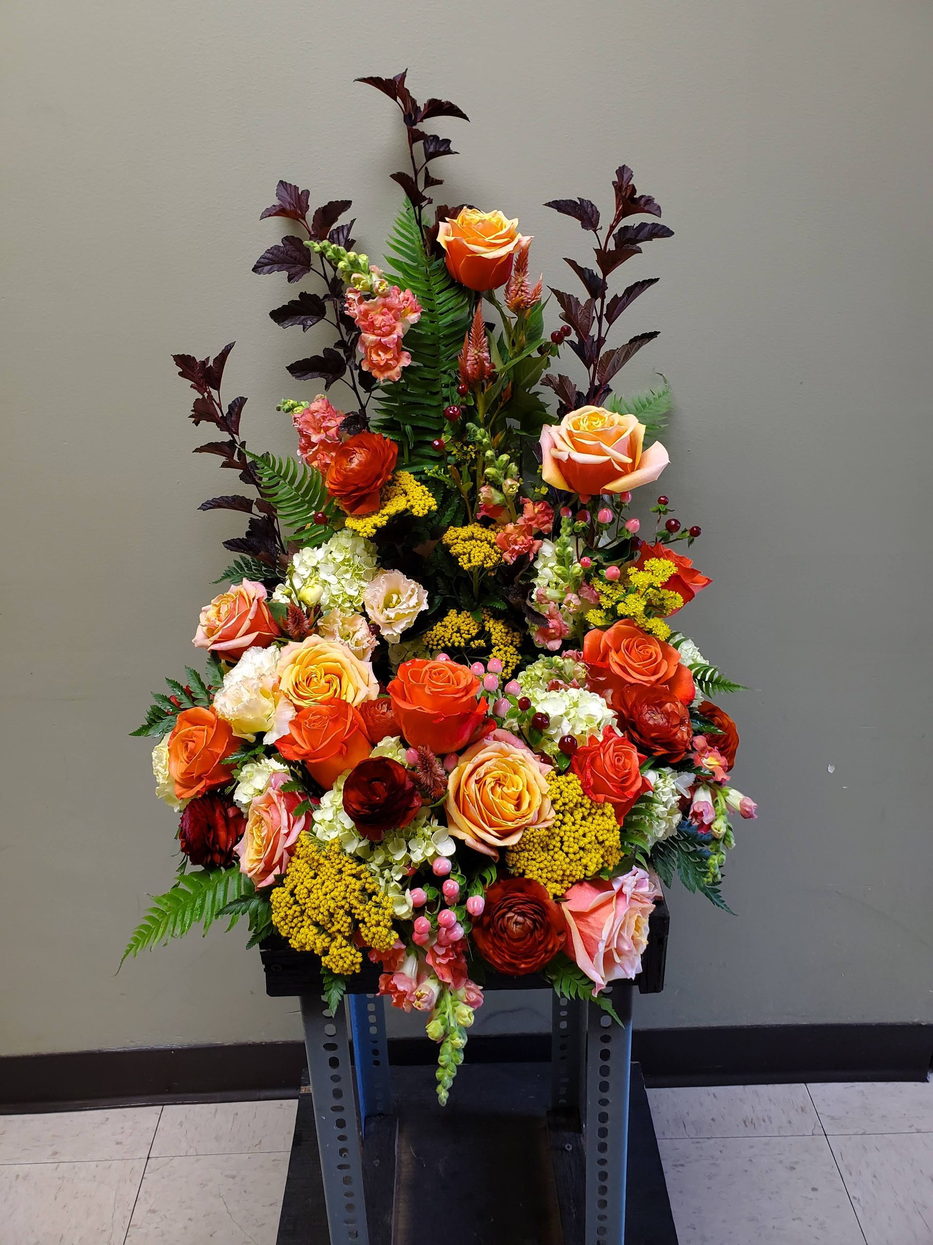 A large bouquet of flowers is sitting on a stool.