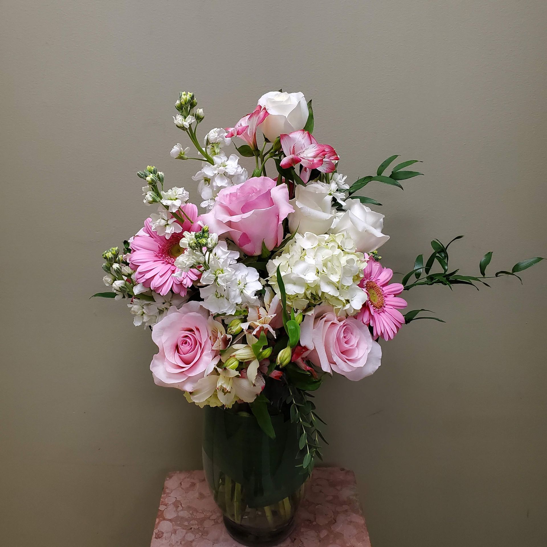 A vase filled with pink and white flowers is sitting on a table.
