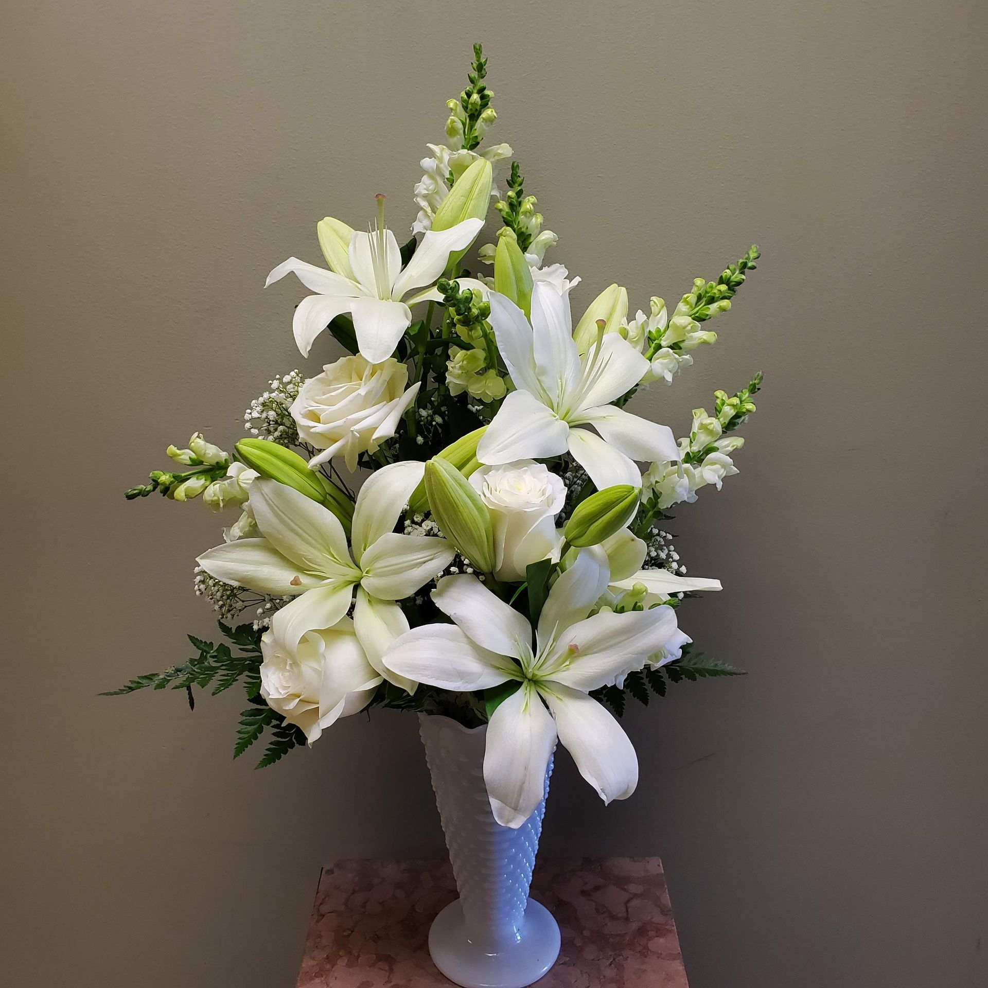A vase filled with white flowers is sitting on a table.
