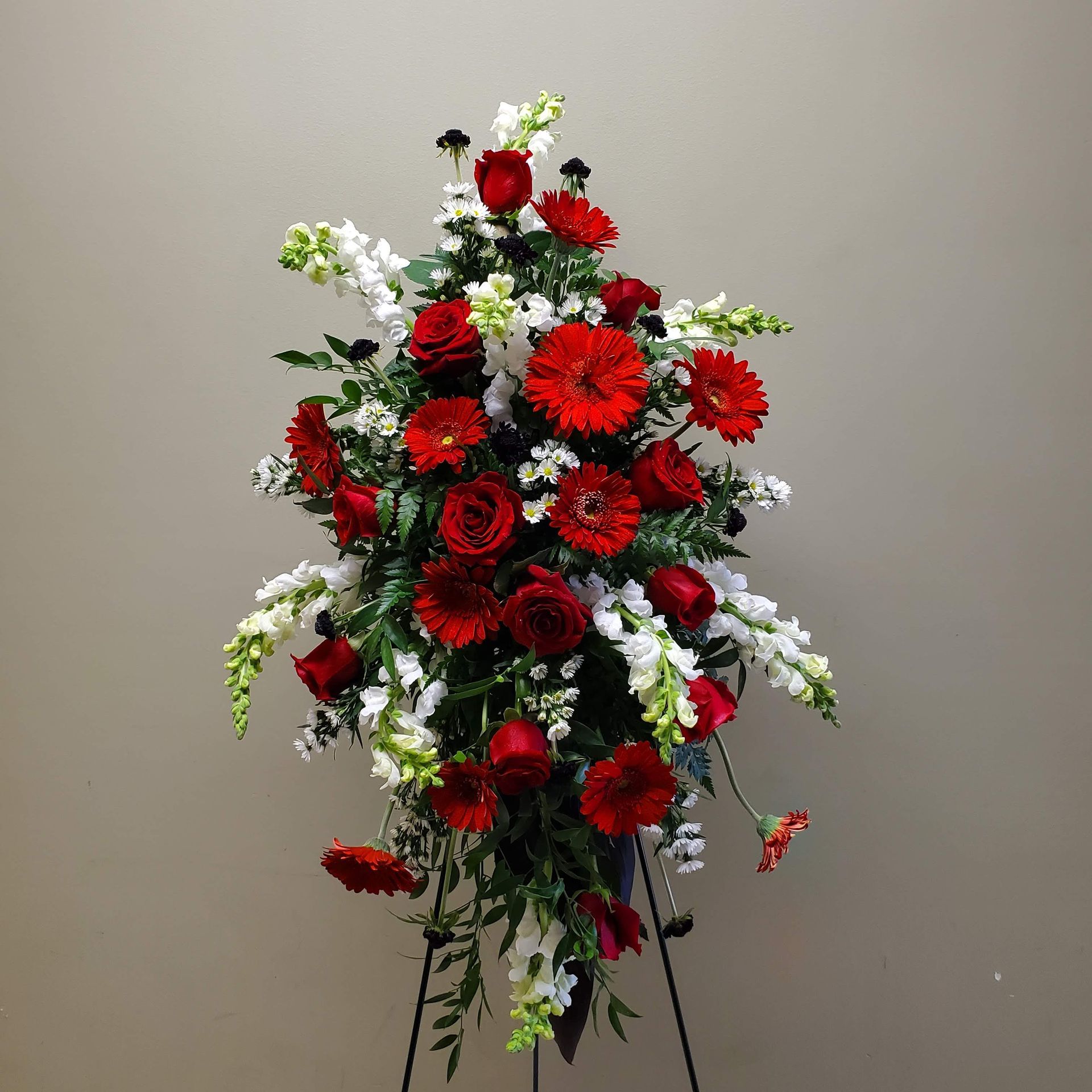 A display of red and white flowers on a stand.