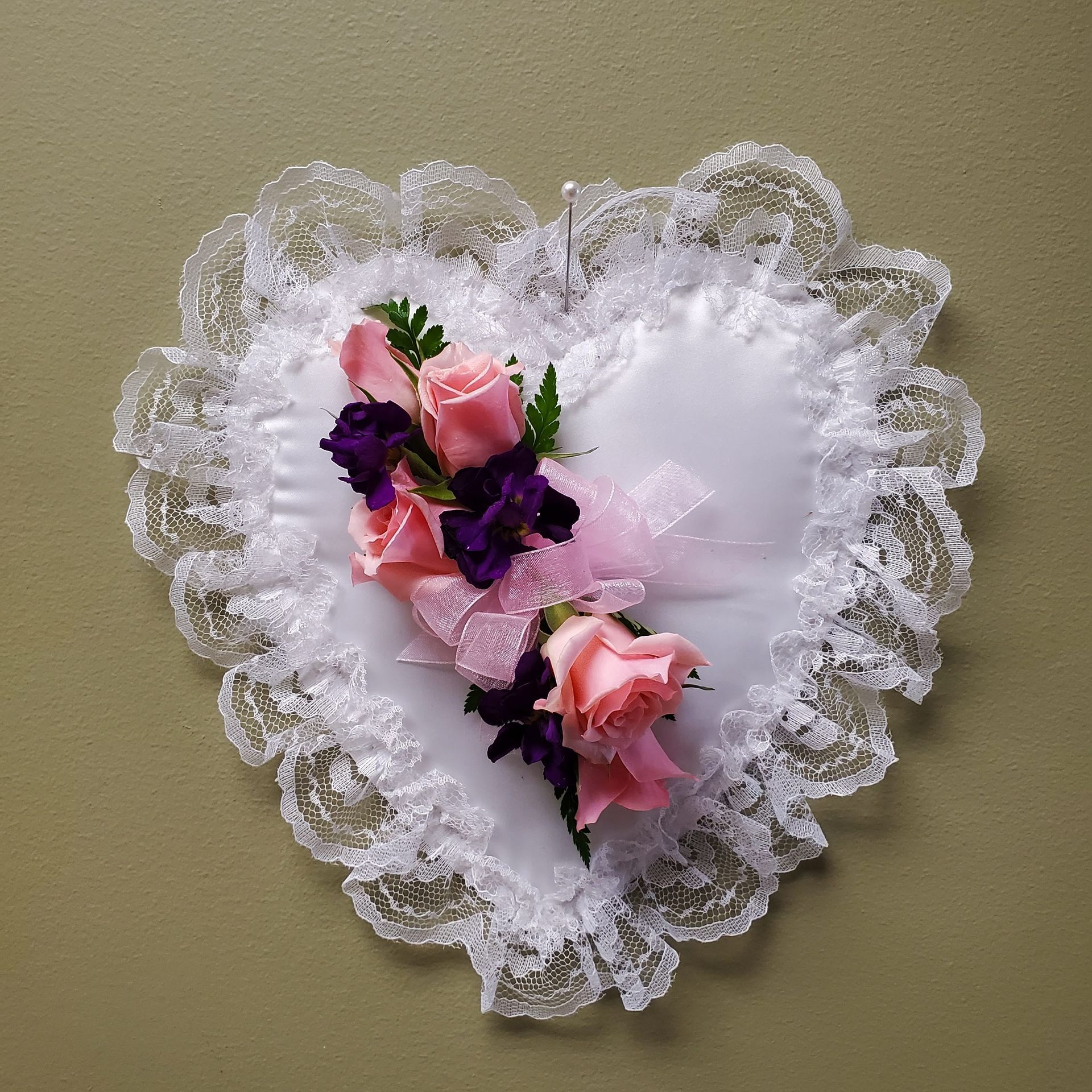 A heart shaped pillow with pink and purple flowers on it.