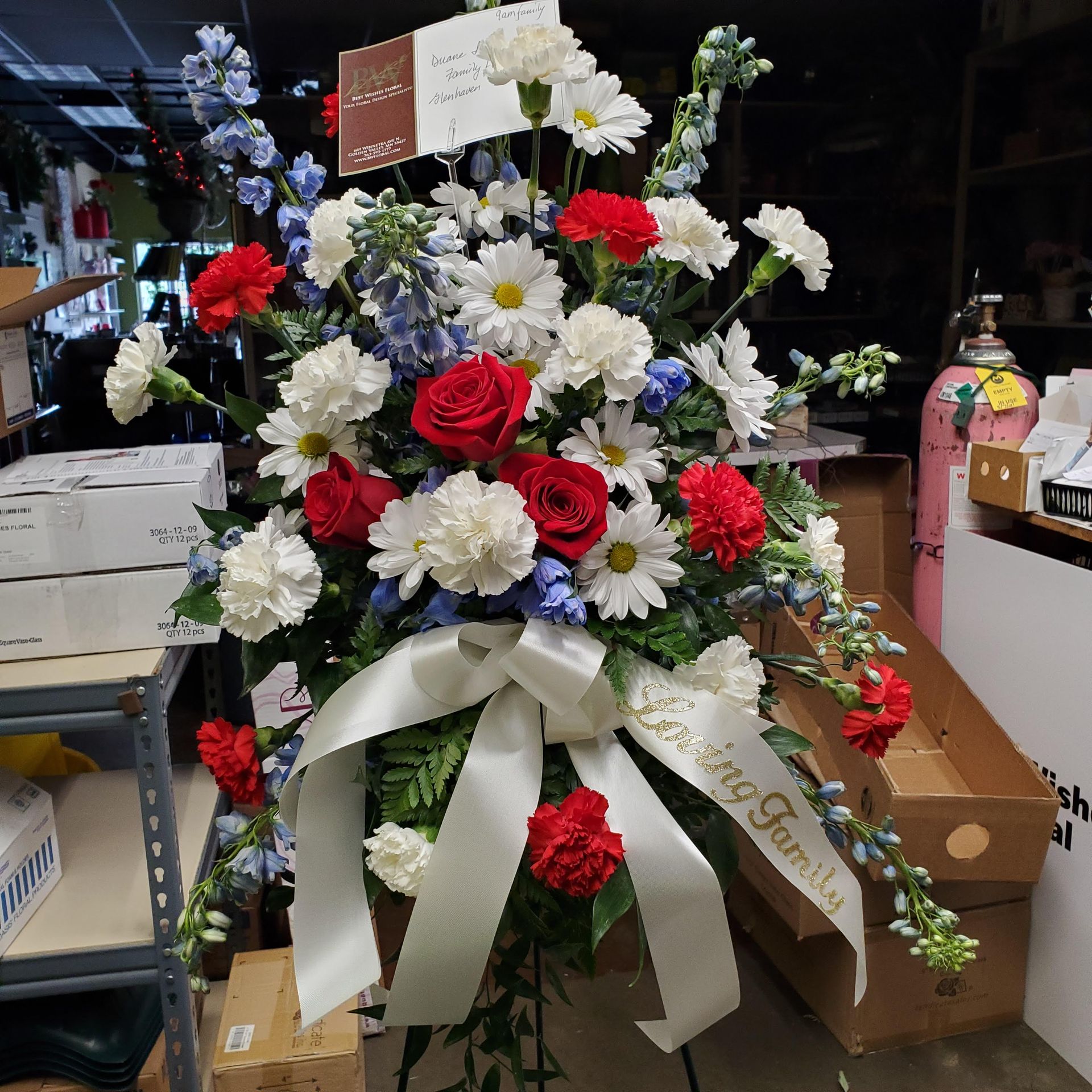 A bouquet of red white and blue flowers with a ribbon that says love my family.