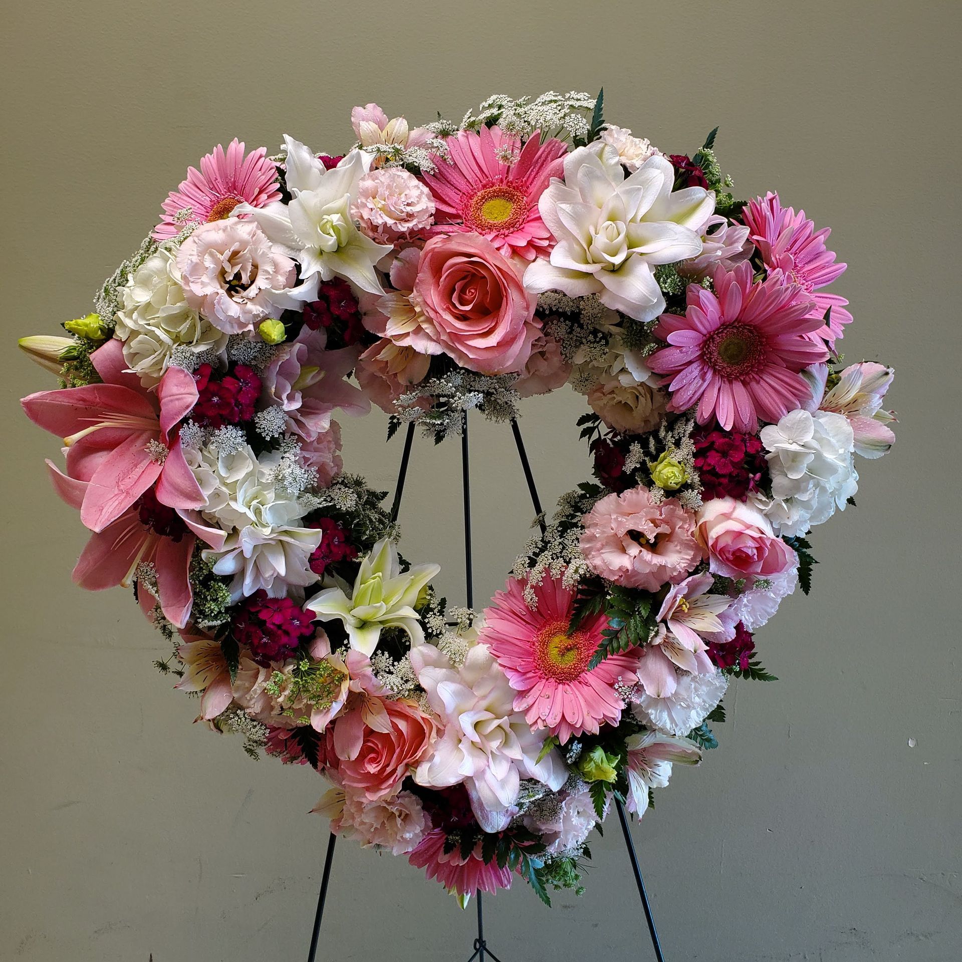 A heart shaped wreath of pink and white flowers.
