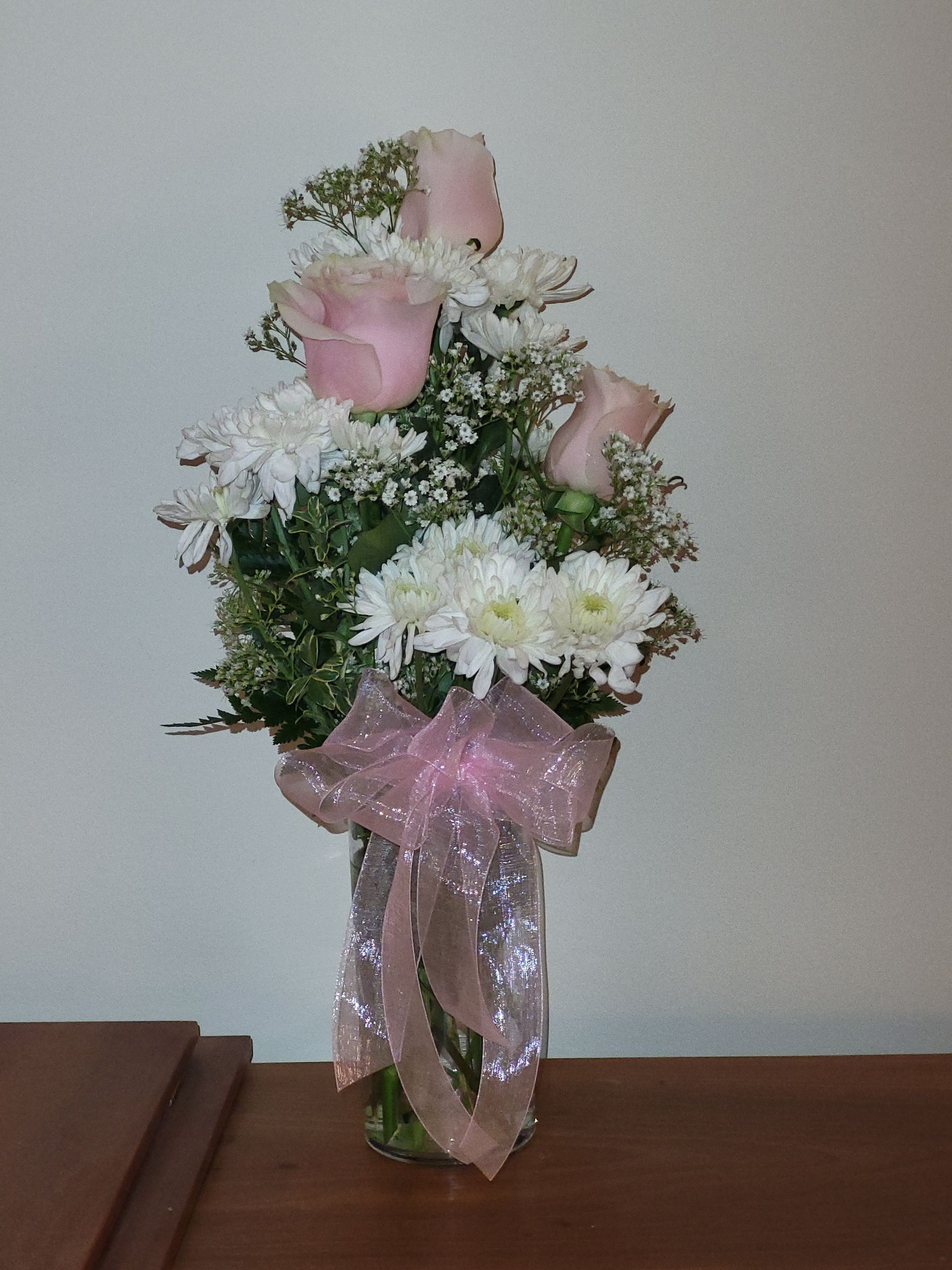 A vase filled with pink roses and white daisies.