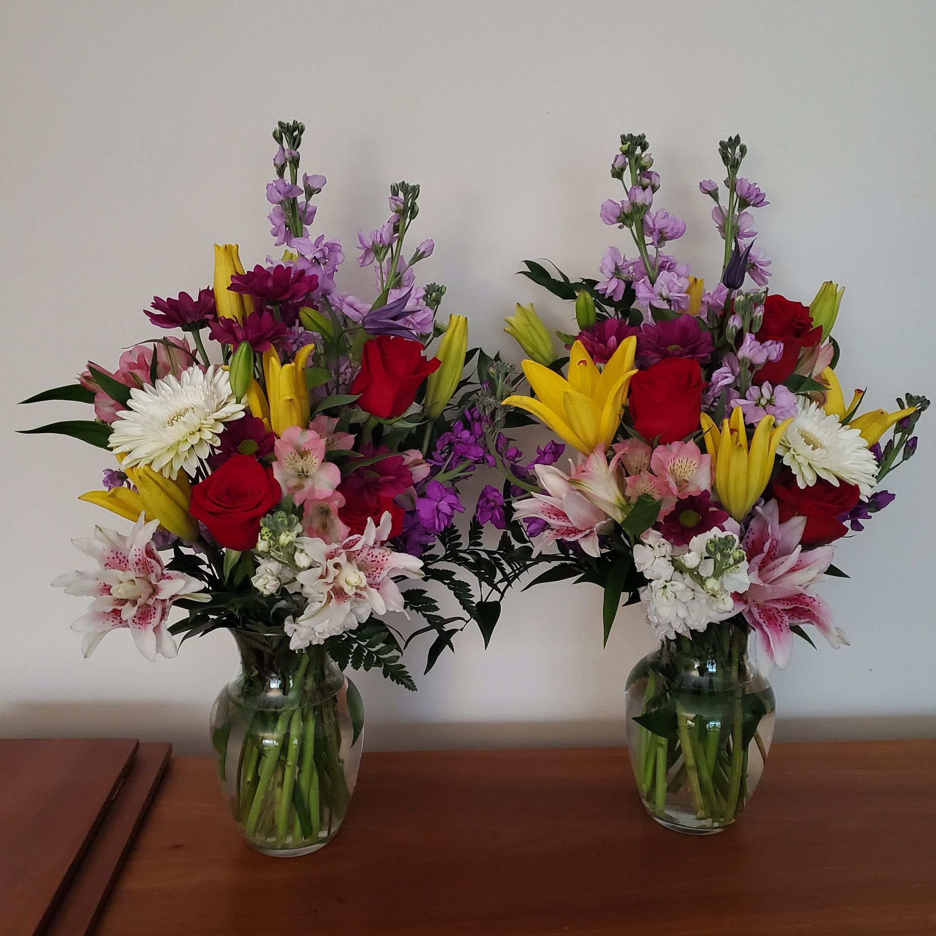 Two vases filled with colorful flowers on a table.
