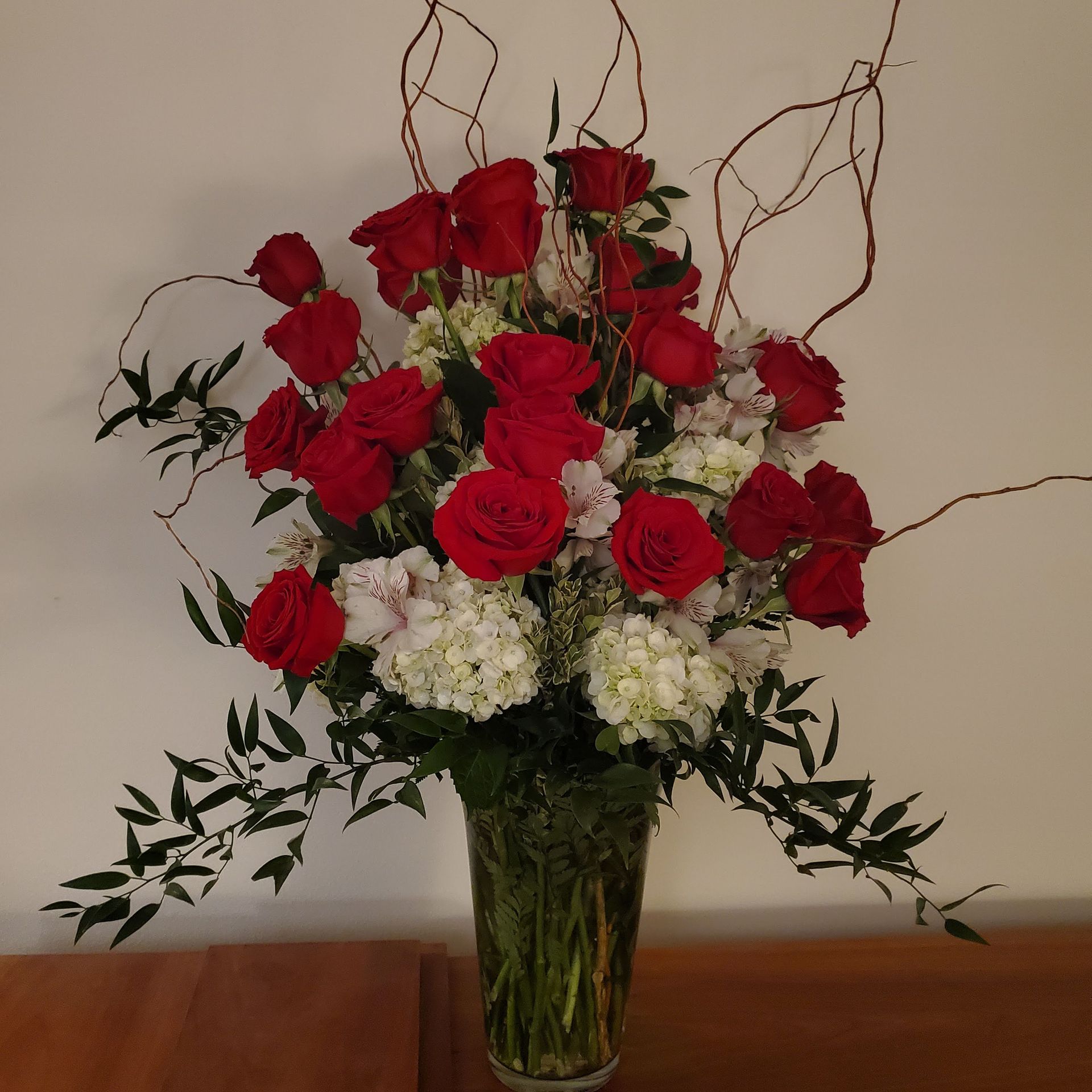 A vase filled with red roses and white flowers.