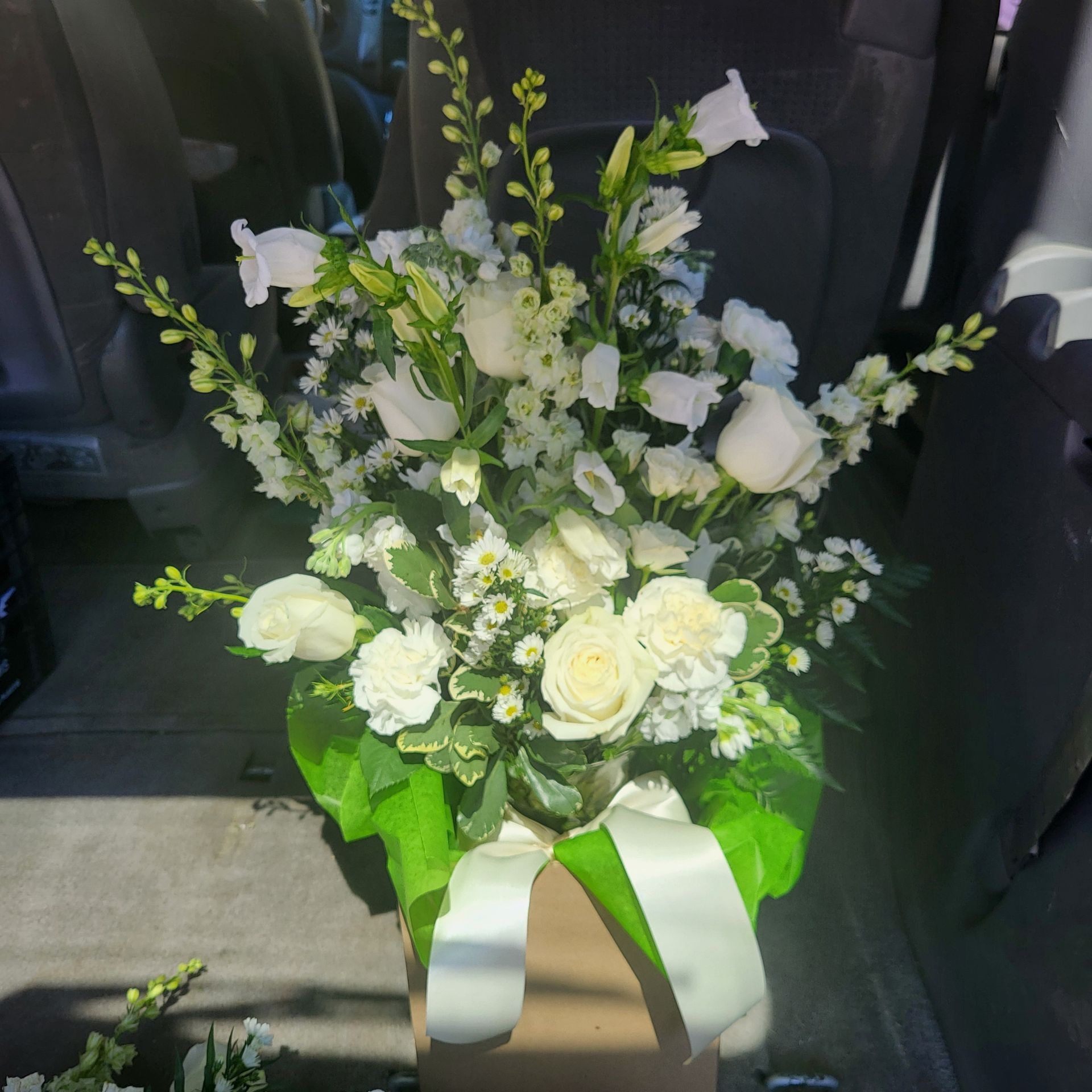 A bouquet of white flowers in a box with a green ribbon.