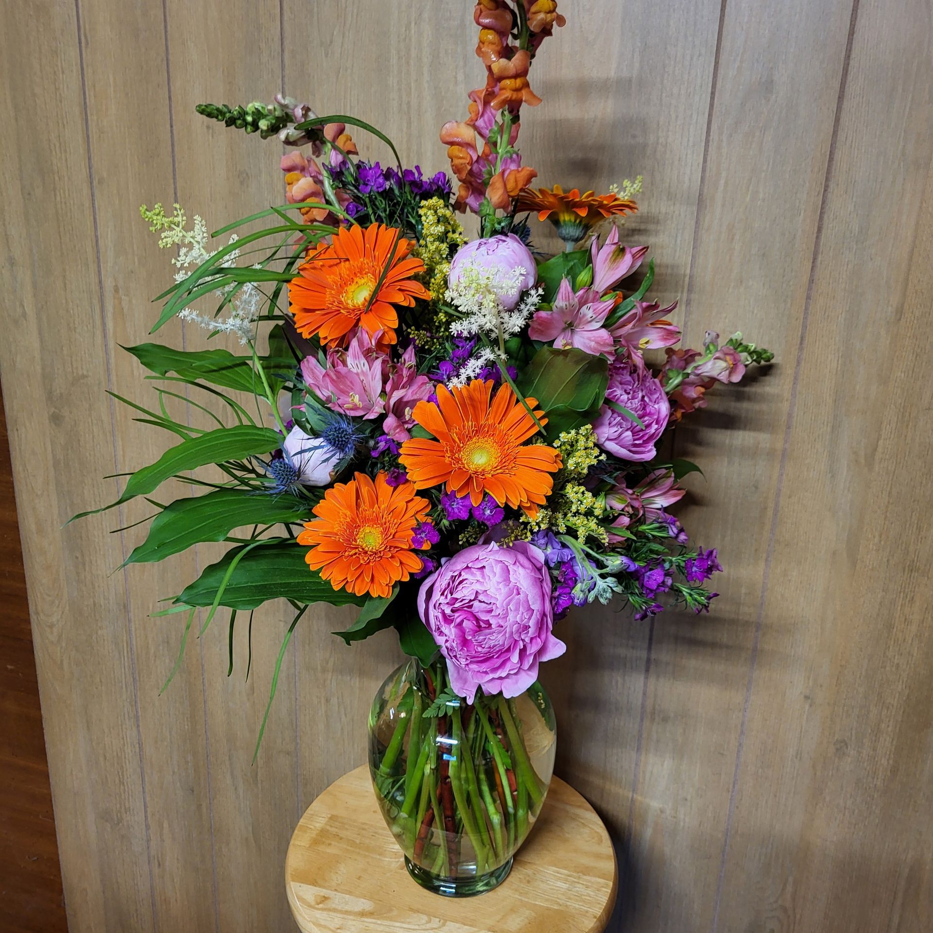 A vase filled with flowers is sitting on a wooden table.