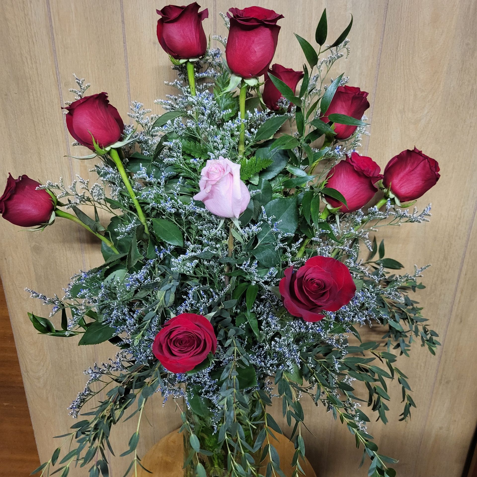 A vase filled with red roses and pink flowers.