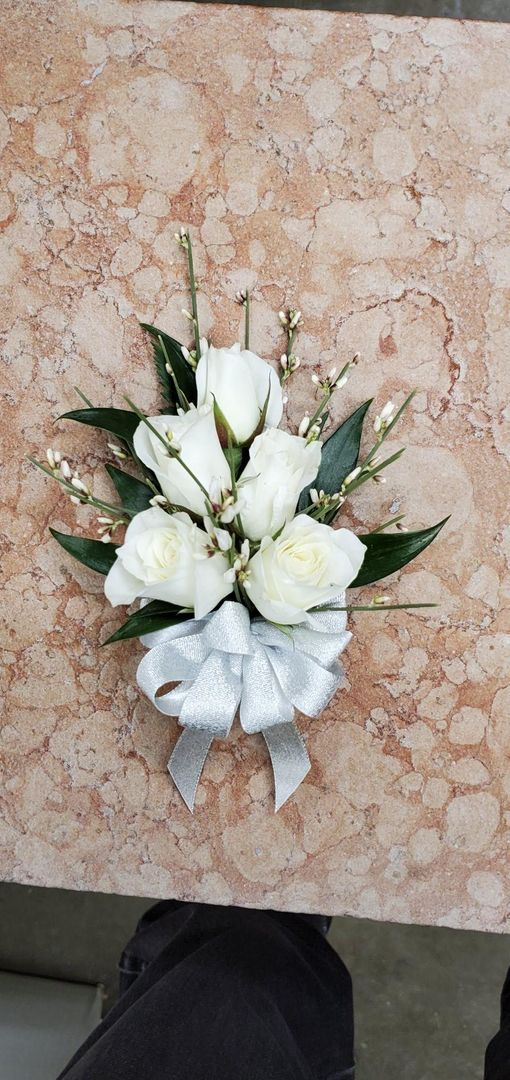 A bouquet of white flowers with a white bow on a table.