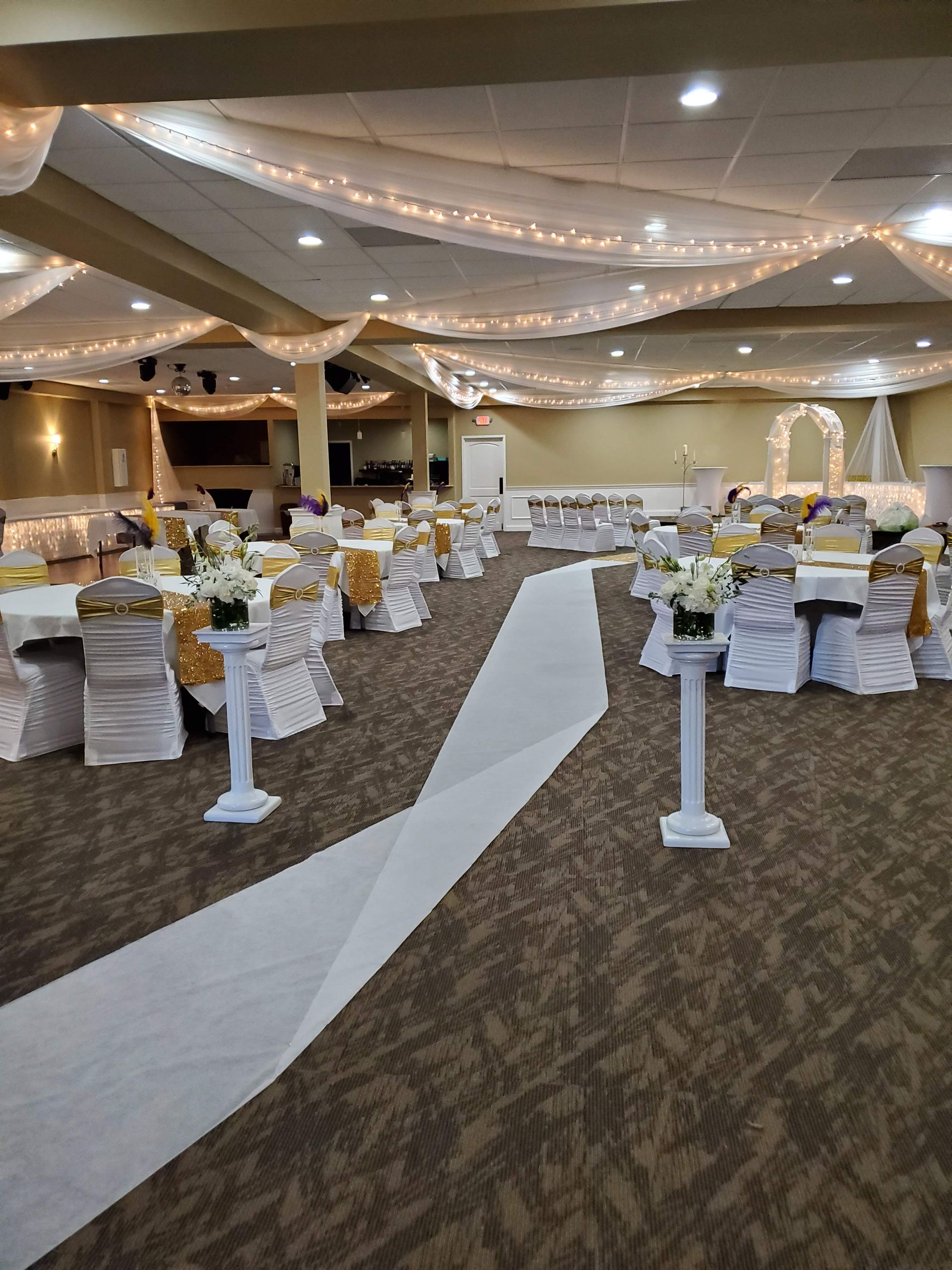 A large room with tables and chairs set up for a wedding reception.