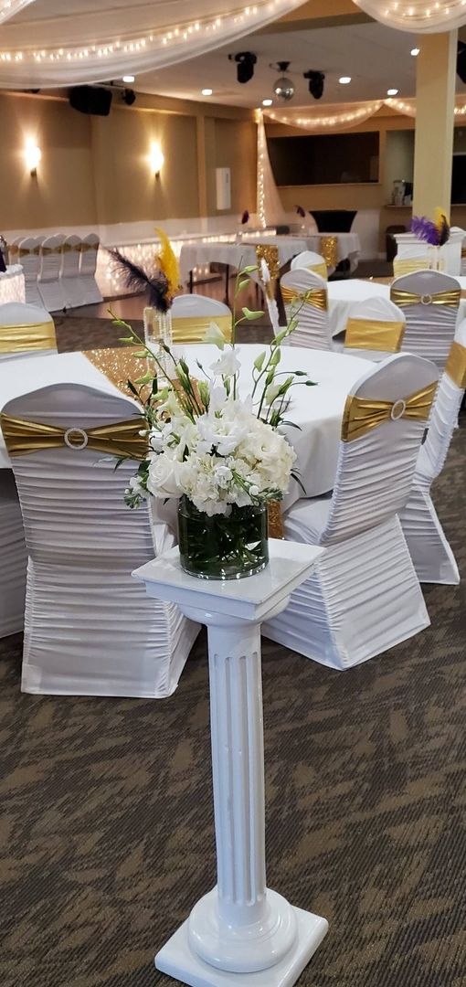 A vase of flowers is sitting on top of a white pedestal in a room.