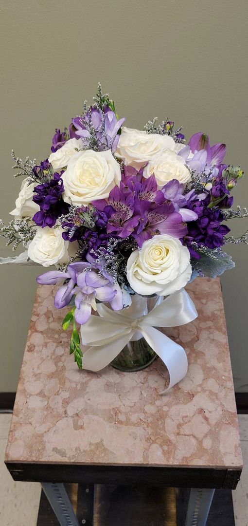 A bouquet of flowers is sitting on a wooden stool.