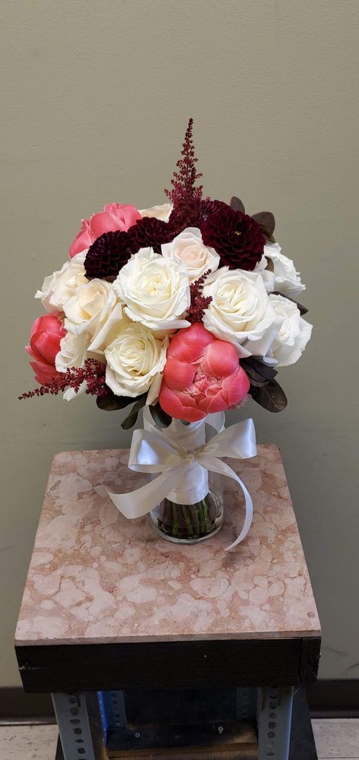 A bouquet of flowers is sitting on a wooden stool.
