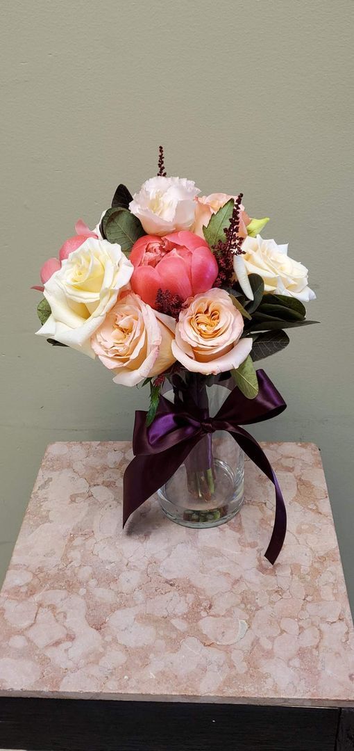 A bouquet of flowers is sitting on a wooden stool.