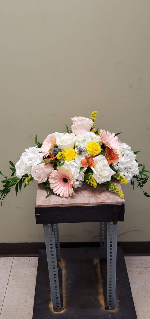 A bouquet of flowers is sitting on a wooden stool.