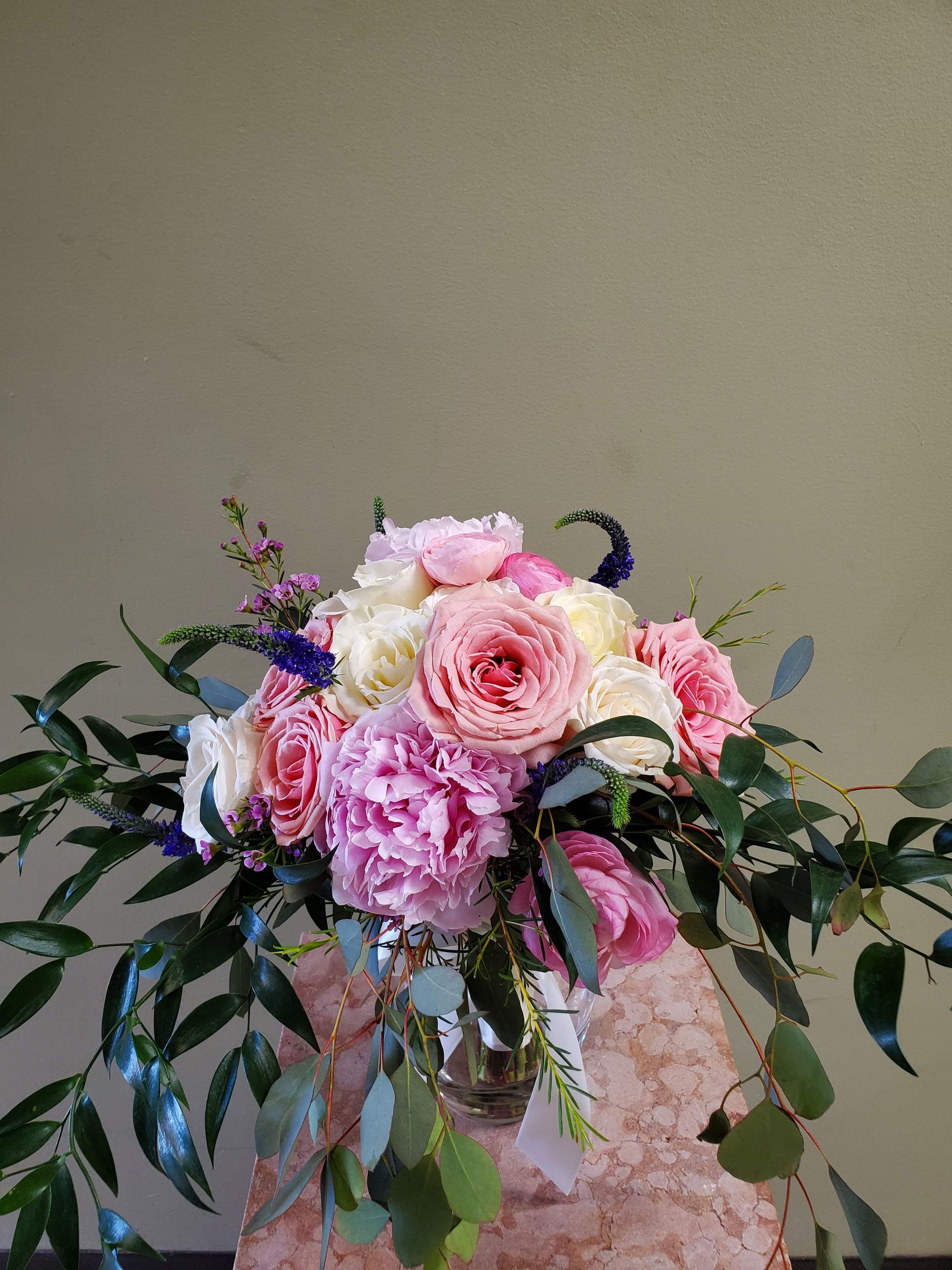 A bouquet of flowers is sitting on a wooden stool.