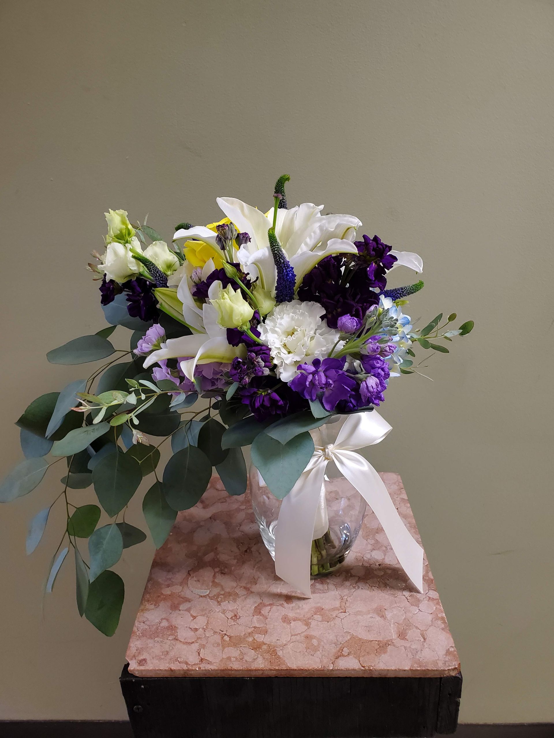 A bouquet of flowers is sitting on a wooden stool.