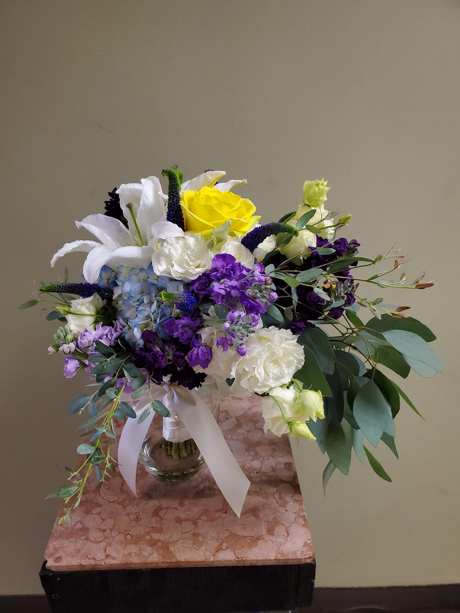A bouquet of flowers is sitting on a wooden stool.