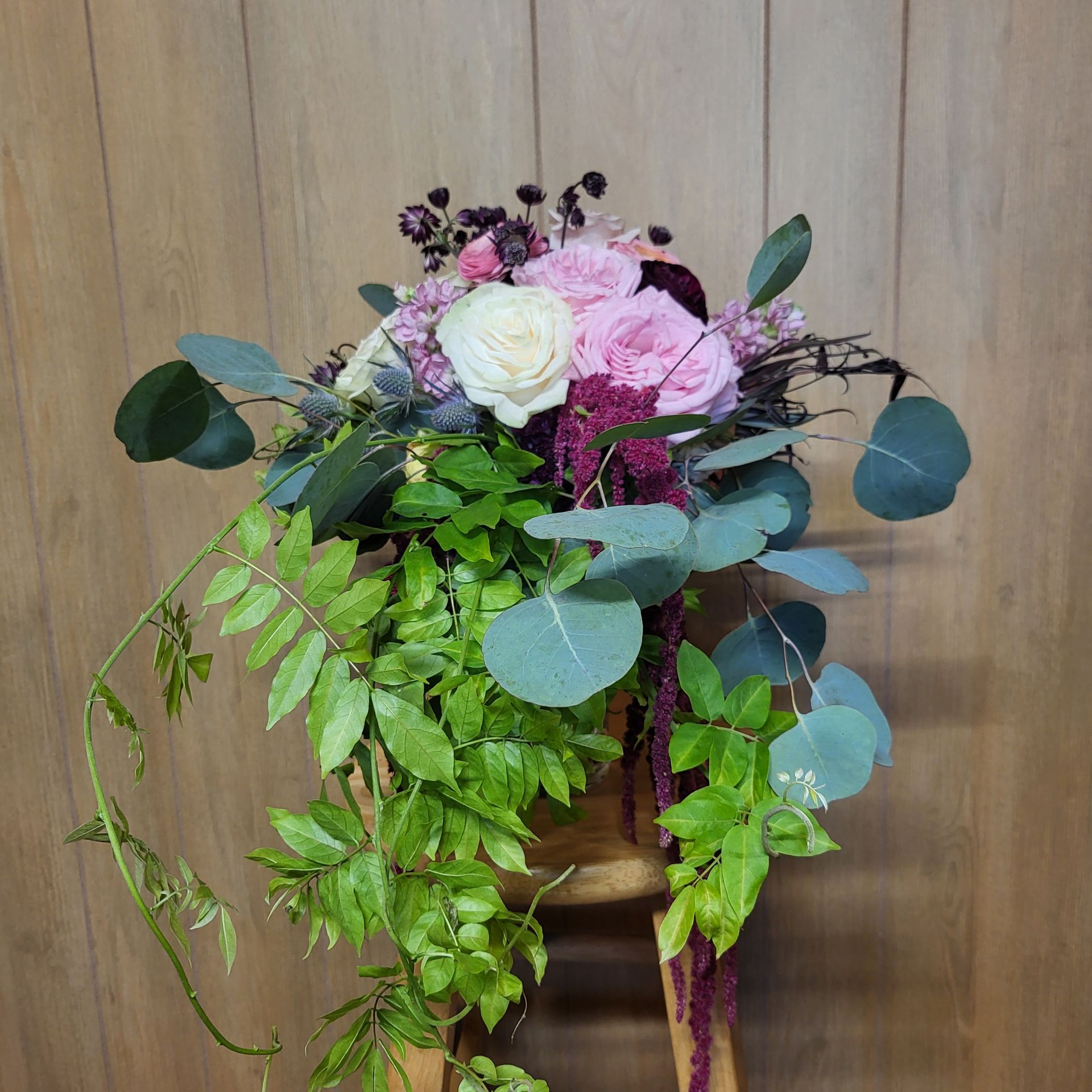 A bouquet of flowers is sitting on a wooden stool.